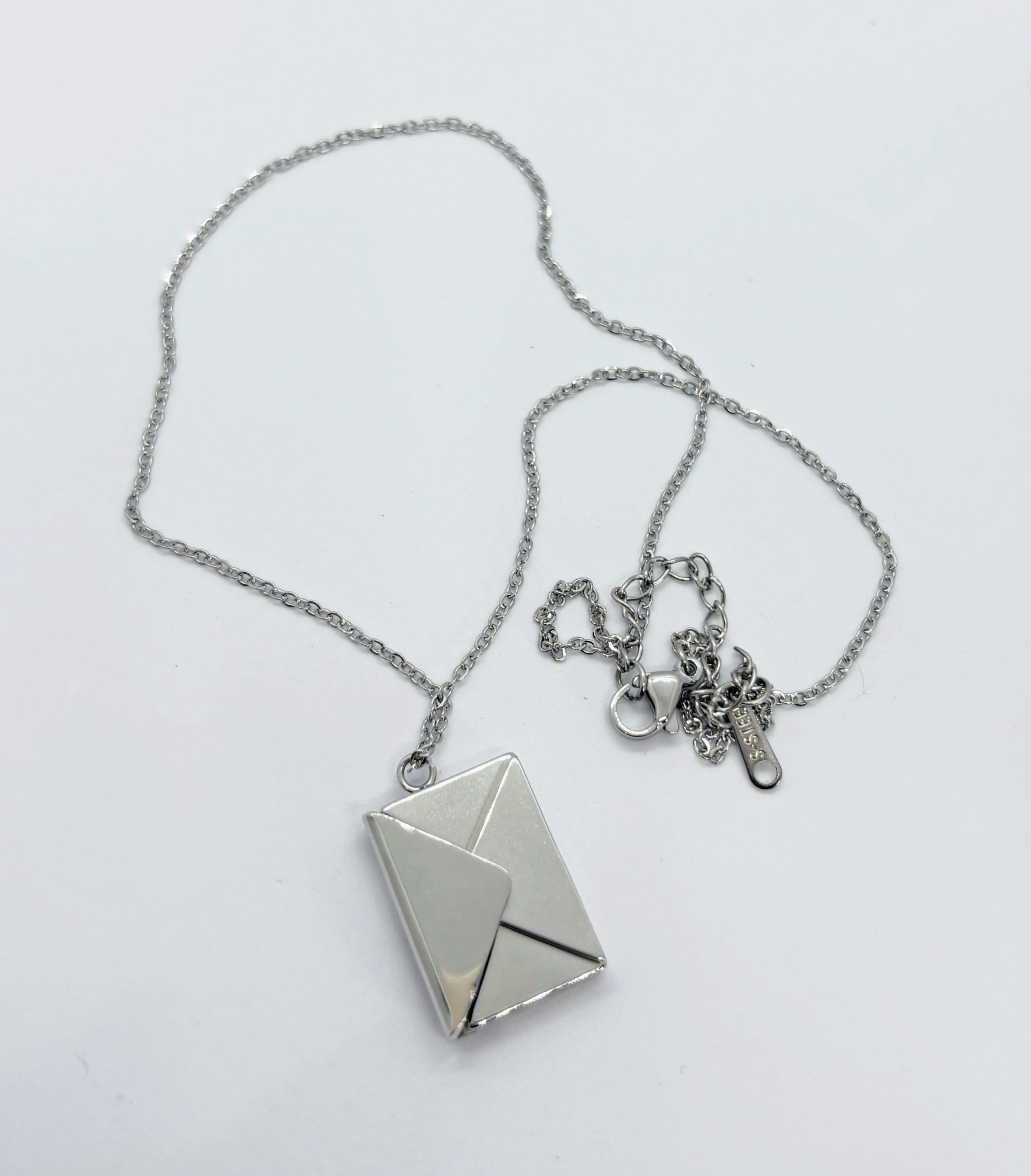 Silver chain necklace with a small envelope-shaped pendant resembling a folded letter, shown on a white background