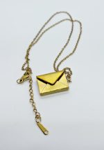 Gold envelope-shaped locket pendant on a delicate gold chain with lobster clasp and extender, photographed on a white background.