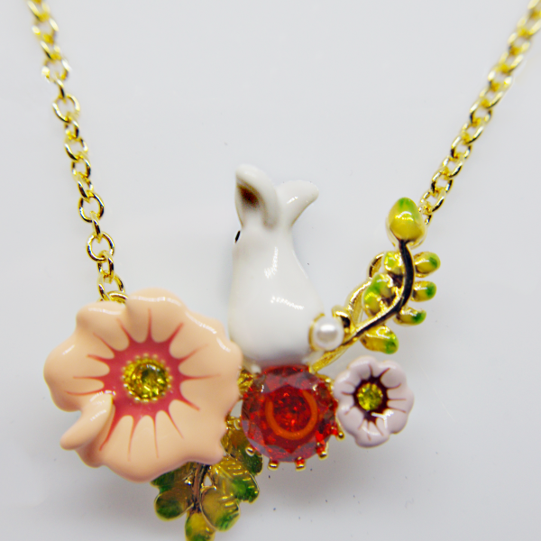 Gold-chain pendant with a small white rabbit amid enamel flowers, a peach blossom, red gem and green leaves.