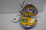 Open heart locket enameled with a tiny unicorn carousel on yellow, hanging from a silver chain with a white bunny charm.
