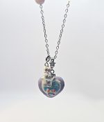 Silver chain with a purple heart pendant showing a blue center, pink bow, small white character, and tiny star charm.