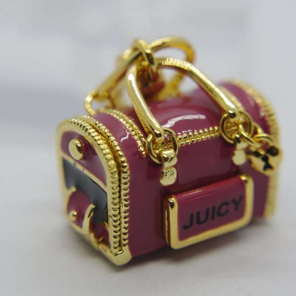 Miniature glossy pink handbag charm with gold hardware and zipper details, front plate labeled "JUICY".