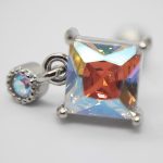 Square faceted iridescent crystal earring in silver prongs with a small beaded round charm bearing a tiny opalescent stone.