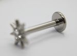 Metal labret earring with flat disc back and star-shaped prong holding a small clear gem on a white surface.