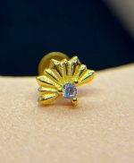 Small gold stud earring shaped like a stylised fan with ridged petals and a central clear gemstone, shown in close-up on skin.