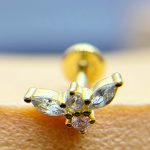 Close-up of a diamond stud earring on skin with a blurred blue background