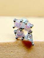 Close-up of a silver earring with three iridescent round opal stones in prong settings and a small triangular clear gem.