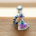 Close-up of a silver curved stud earring with a heart-shaped iridescent purple gemstone set against textured skin.