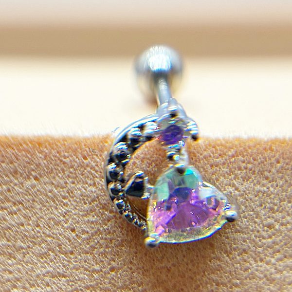 Close-up of a silver curved stud earring with a heart-shaped iridescent purple gemstone set against textured skin.
