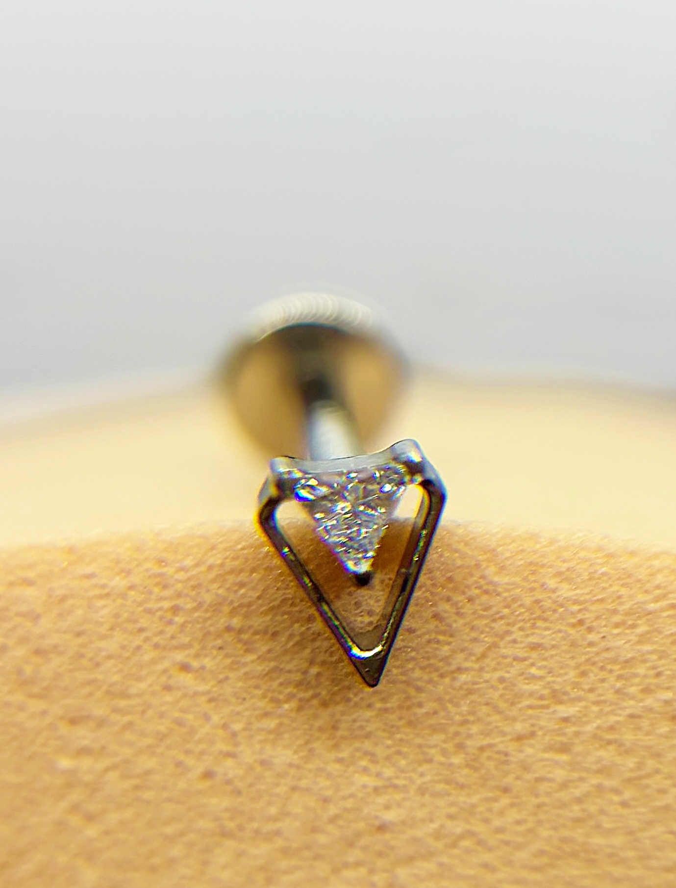 Close-up of a triangular diamond nose stud piercing in skin