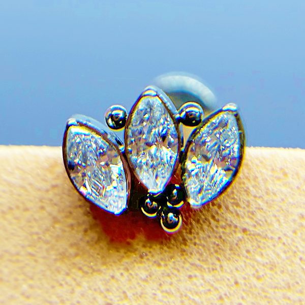 Close-up of a silver ring with three marquise-cut clear stones and small black beads on a finger