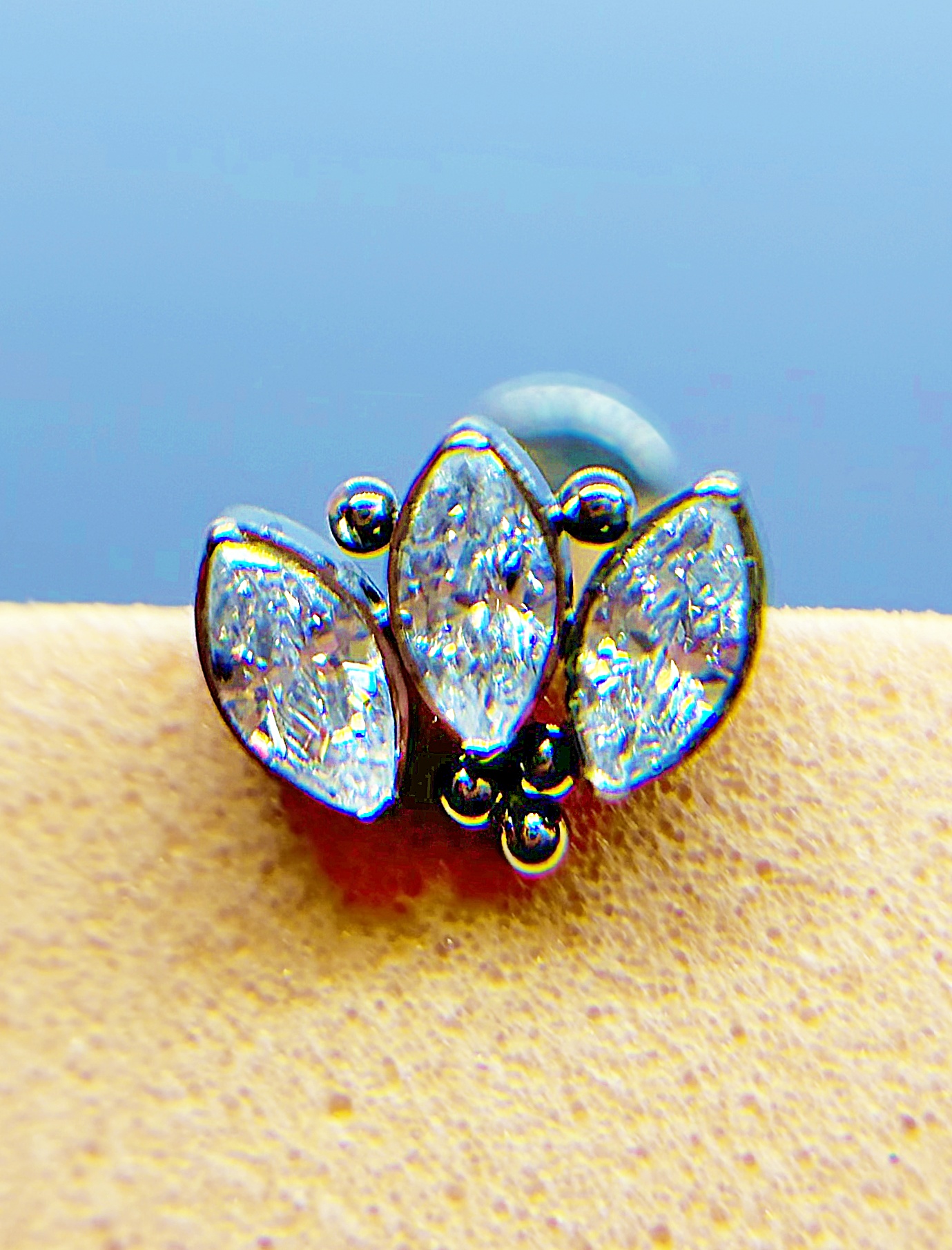 Close-up of a silver ring with three marquise-cut clear stones and small black beads on a finger