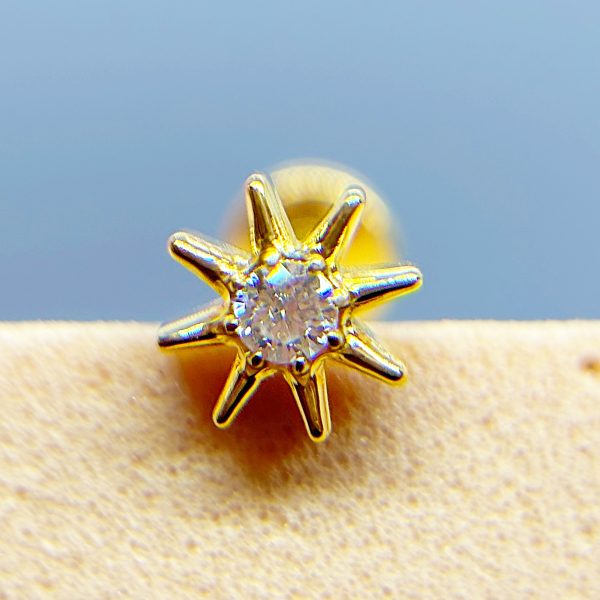 Close-up of a gold star-shaped diamond stud earring against a blue background