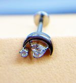 A close-up of a curved silver earring with clear gems on a blurred background