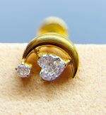 Close-up of a gold and diamond nose stud with a curved crescent design on skin