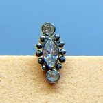 Close-up of a silver stud earring with clear gemstones on a blue background