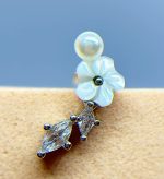 Close-up of a pearl and crystal flower-shaped earring against a blue background