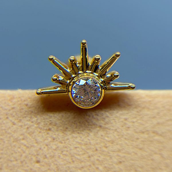 Gold starburst ring with a clear central gemstone on a blue background