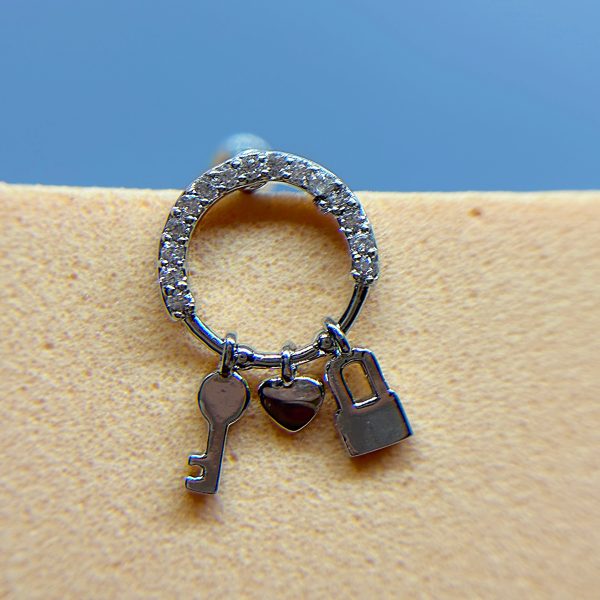 Silver hoop earring with key, heart and padlock charms on a skin-toned background
