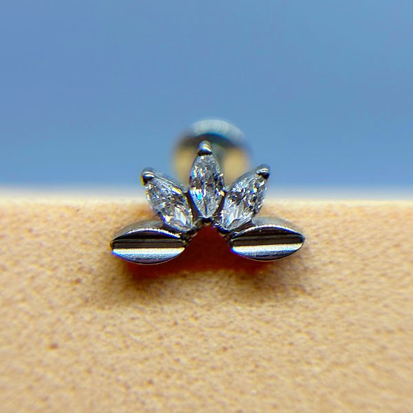 Close-up of a diamond and silver nose stud on skin against a blue background