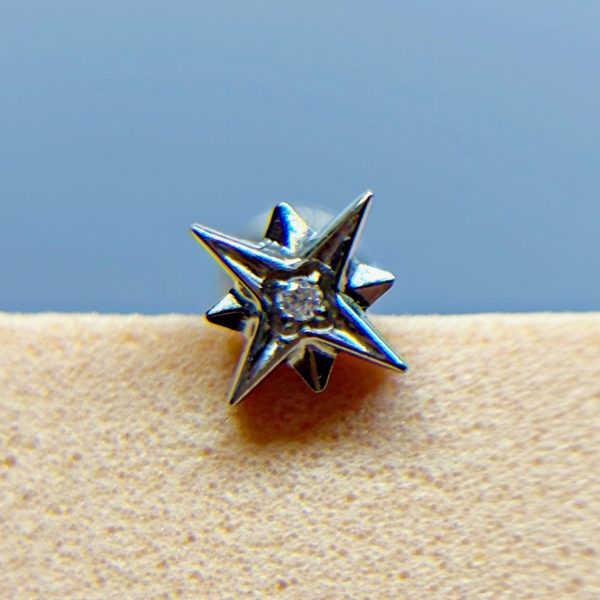 Close-up of a silver star-shaped stud earring with a small clear gem