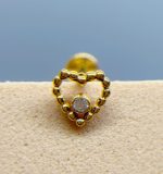 Close-up of a gold beaded earring with a central clear stone against a soft blue background