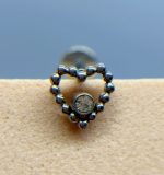 Heart-shaped beaded stud earring with a clear central gem on skin