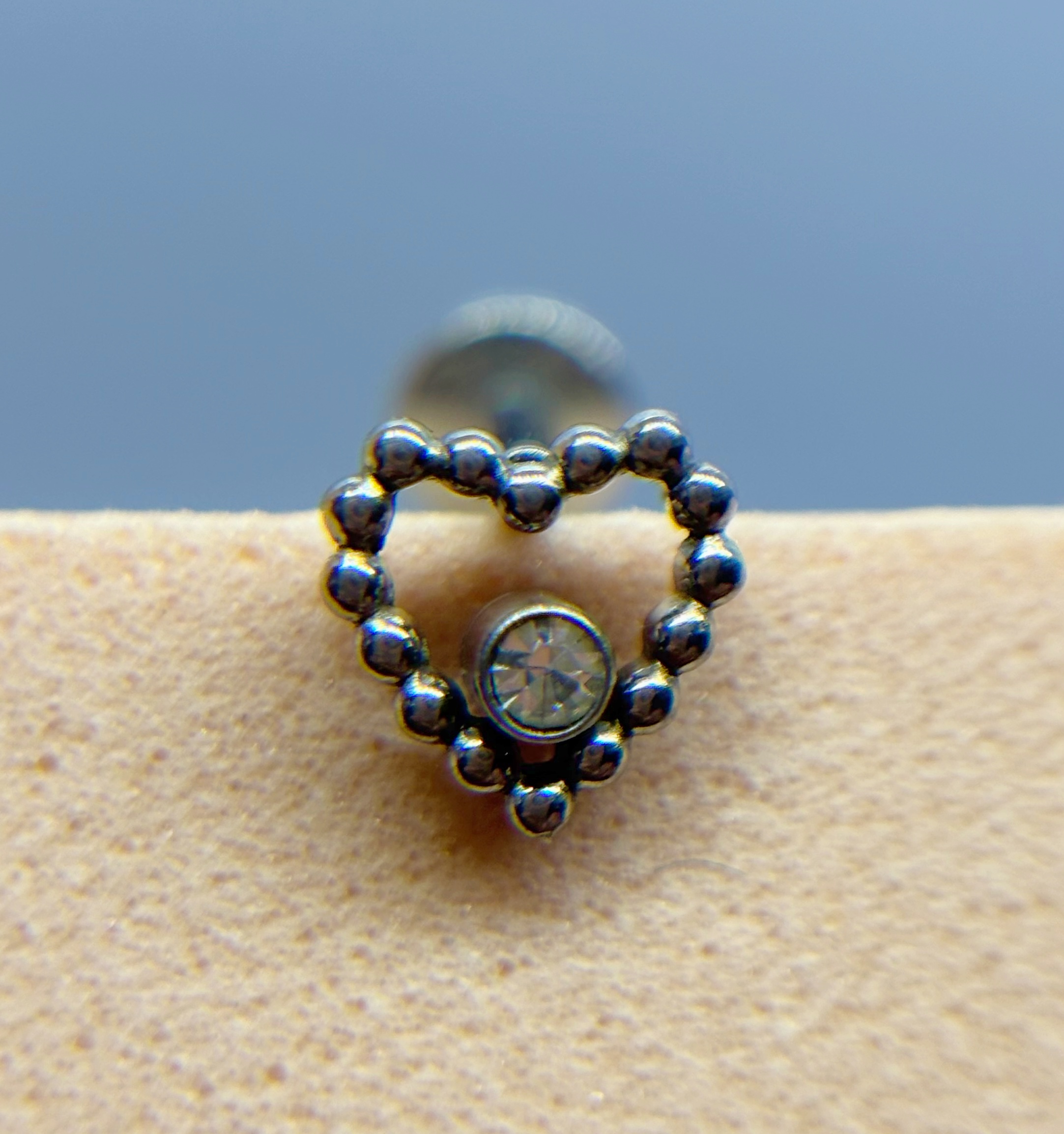 IMG_9372 Heart-shaped beaded stud earring with a clear central gem on skin