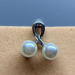 Close-up of a pearl drop earring with a silver loop against skin