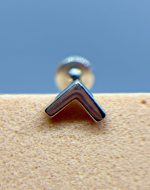 Close-up of a chrome chevron-shaped metal fitting against a blue background and speckled beige surface