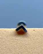 Close-up of a metal staple or clip on a textured surface against a blue background