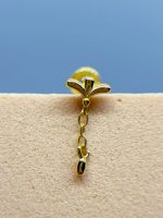 Gold chain earring with a flower-shaped stud against a blue background on skin