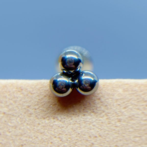 Three shiny metal balls stacked in a pyramid on a beige surface against a blue background