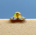 Close-up of a gold stud earring with two clear stones against a blue background