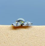 Marquise-cut diamond stud earring on a beige surface against a blue background