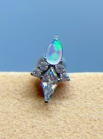 Close-up of a gemstone ear stud with an iridescent teardrop stone and clear crystals on skin