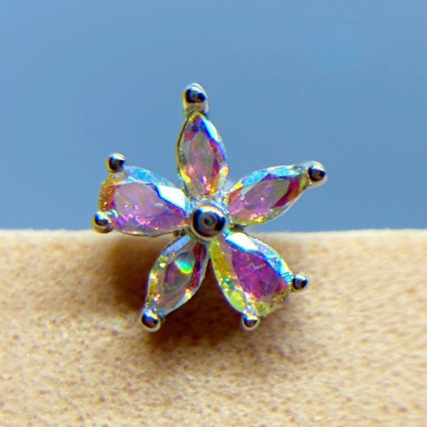 Close-up of a iridescent crystal flower stud earring against a blue background