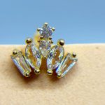 Close-up of a diamond and gold floral earring against blue sky and skin-toned background