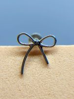 Close-up of a metal wire bow clasp on beige fabric against a blue background